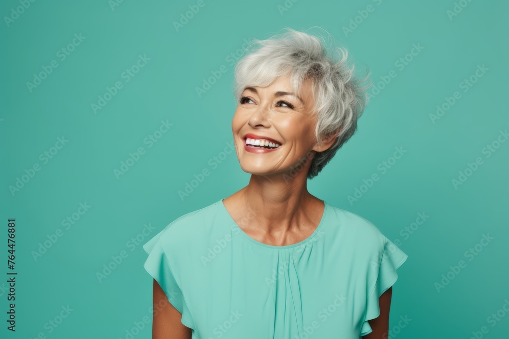 Smiling senior woman looking at the camera over turquoise background Smiling senior woman looking at the camera over turquoise background