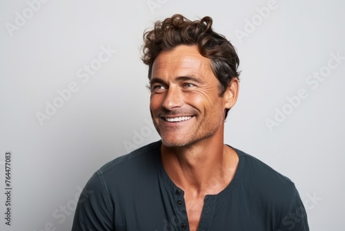 Portrait of a handsome man smiling while looking away over gray background