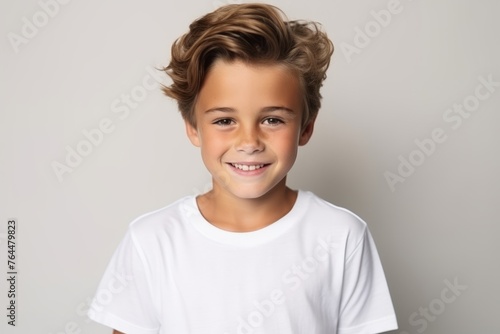 Portrait of a cute little boy in white t-shirt on grey background © Inigo