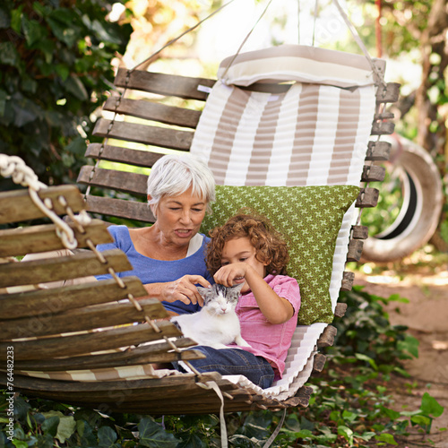 Backyard, grandmother and boy with cat, relax and sunshine with weekend break and vacation. Family, old woman and grandchild with pet and hammock in a backyard with animal, bonding together in spring