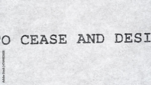 A macro CU tracking shot of the text Cease and Desist printed on paper standard bold font