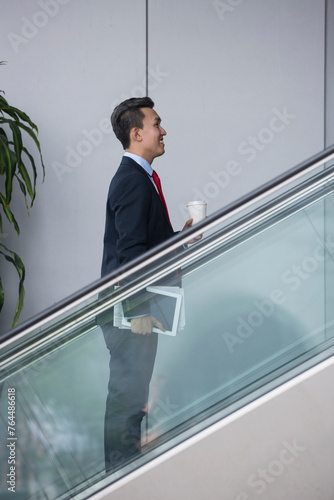 Chinese businessman standing on an escalator.