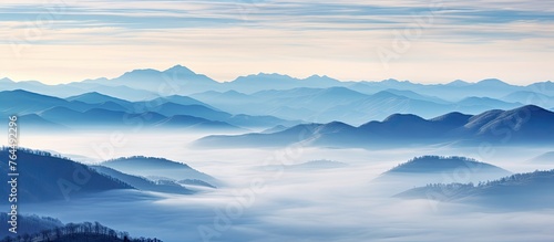 A scenic view of misty mountains concealed in fog with low-lying clouds nestled in a serene valley