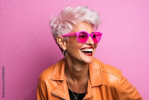 Fashionable woman with pink sunglasses and short hair on pink background © Inigo