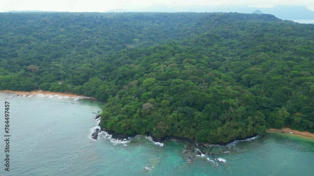 Aerial view from the green forest coast from Prince Island with view for Sundy beach resort cover by the trees,Prince Island, Africa. Circular drone shot. Aerial view from the green forest coast from Prince Island with view for Sundy beach resort cover by the trees,Prince Island, Africa. Circular drone shot.