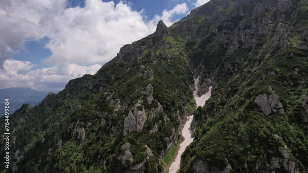 A muddy river flowing through bucegi mountains, green peaks under a blue sky, summer day, aerial view A muddy river flowing through bucegi mountains, green peaks under a blue sky, summer day, aerial view