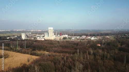 Industrial complex of the Darkov coal mine surrounded by wooded area, the town visible in the background under a clear sky photo