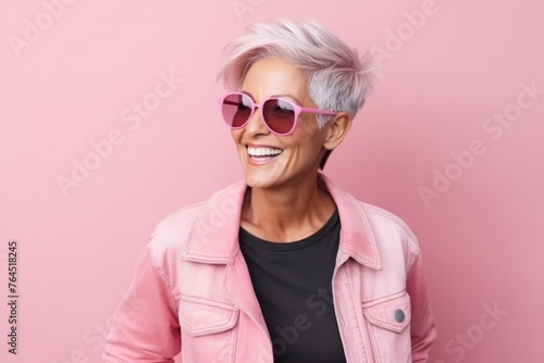 Portrait of a happy senior woman in pink sunglasses over pink background