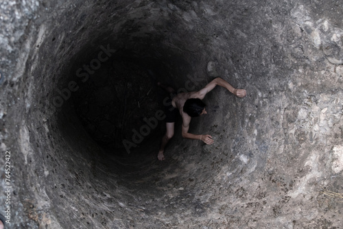 A person trying to get out of a water well photo