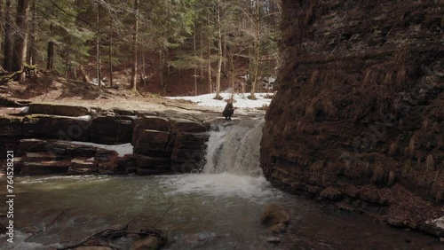 Woman washes face in the waterfall. 