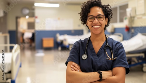Wearing electric blue eyewear, the nurse stands in the hospital hallway, arms crossed, smiling, and sharing a warm thumbup gesture with a hardwood flooring background photo