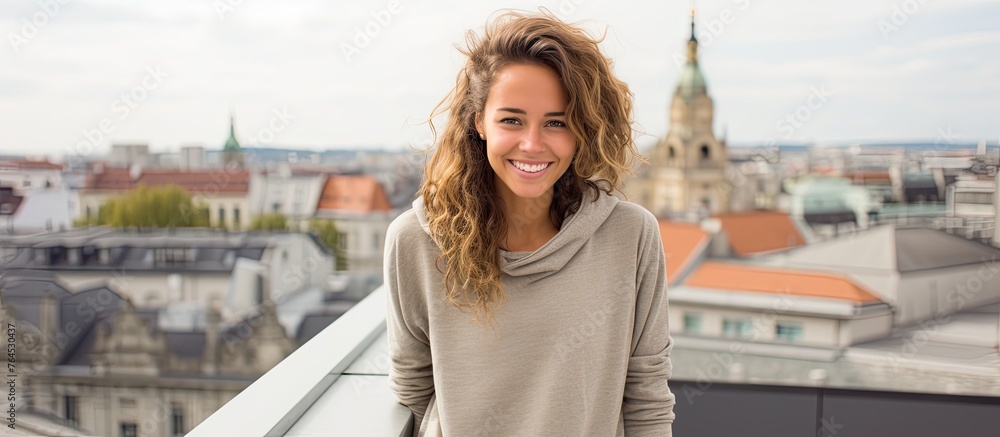 A cheerful female standing on a terrace gazing at an urban cityscape in the distance