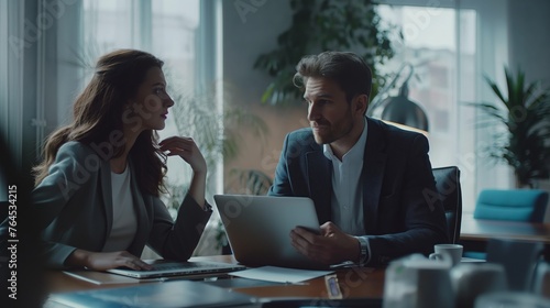 Two business professionals engaging in a serious discussion with a digital tablet in a contemporary office setting.