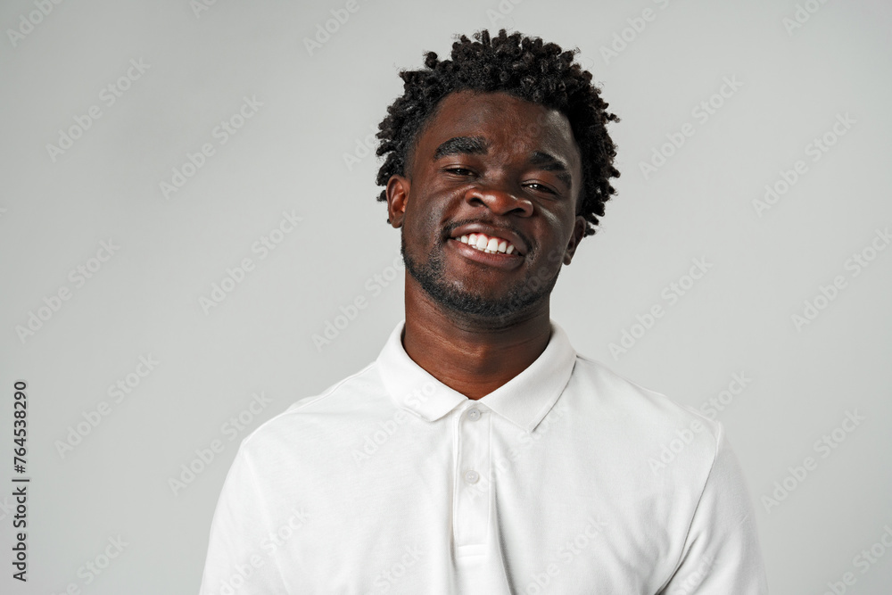 Young African Man With a Joyful Smile in White Shirt Against Gray Background Young African Man With a Joyful Smile in White Shirt Against Gray Background