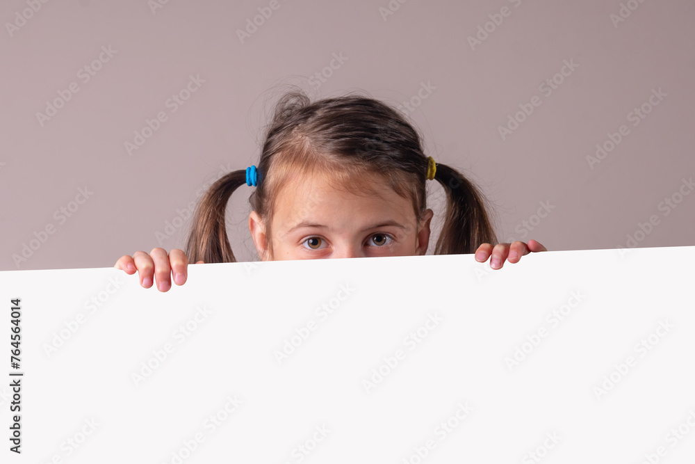 Cheerful attractive young girl behind gray blank banner or empty copy space, Copy space for text or design. Horizontal image. Cheerful attractive young girl behind gray blank banner or empty copy space, Copy space for text or design. Horizontal image.
