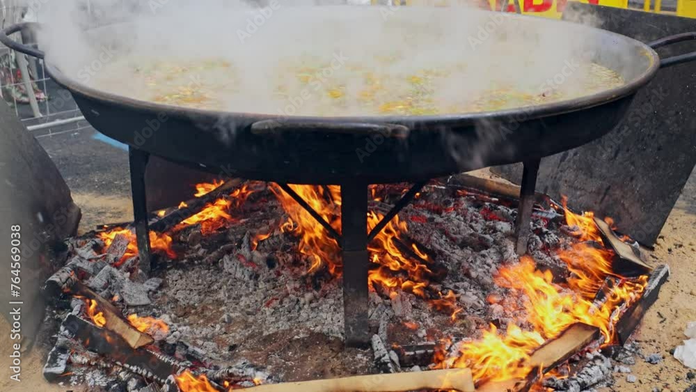 Prepares a delicious paella in a traditional large pan on the street during Las Fallas festival. Valencia, Spain - March 16, 2024. Prepares a delicious paella in a traditional large pan on the street during Las Fallas festival. Valencia, Spain - March 16, 2024.