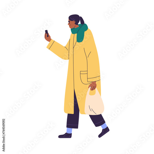 Black woman using mobile phone on the go on street. Person walking and holdin...