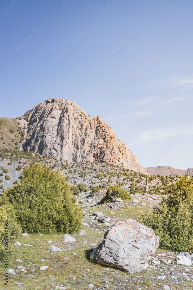 Racing landscape in the Fan Mountains with rocky slopes and vegetation in the morning in Tajikistan, Tien Shan highlands Racing landscape in the Fan Mountains with rocky slopes and vegetation in the morning in Tajikistan, Tien Shan highlands