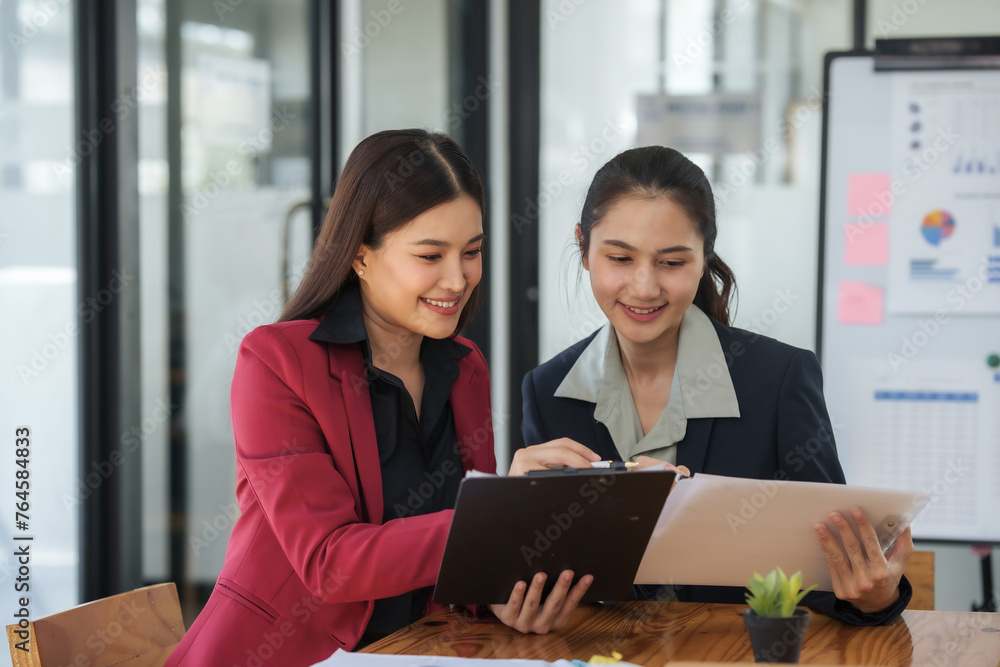 Two women are sitting at a table, one of them is holding a piece of paper Two women are sitting at a table, one of them is holding a piece of paper