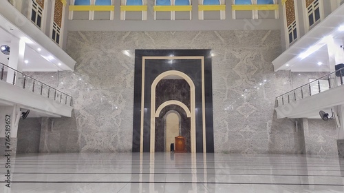 The empty praying hall of mosque with white marby tiled floor and wall