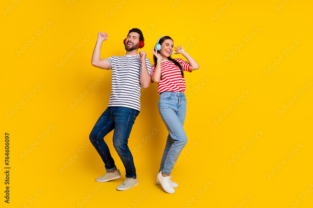 Fototapeta premium Full body portrait of two cheerful people enjoy music dancing empty space isolated on yellow color background
