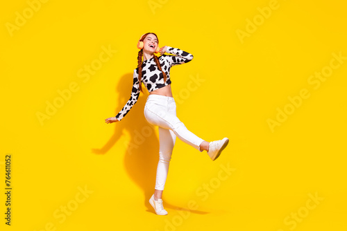 Full body photo of carefree positive lady enjoy listen new playlist headphones dance empty space isolated on yellow color background