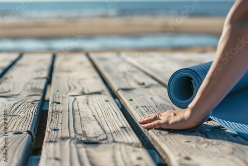 person rolling out yoga mat on wooden beach boardwalk