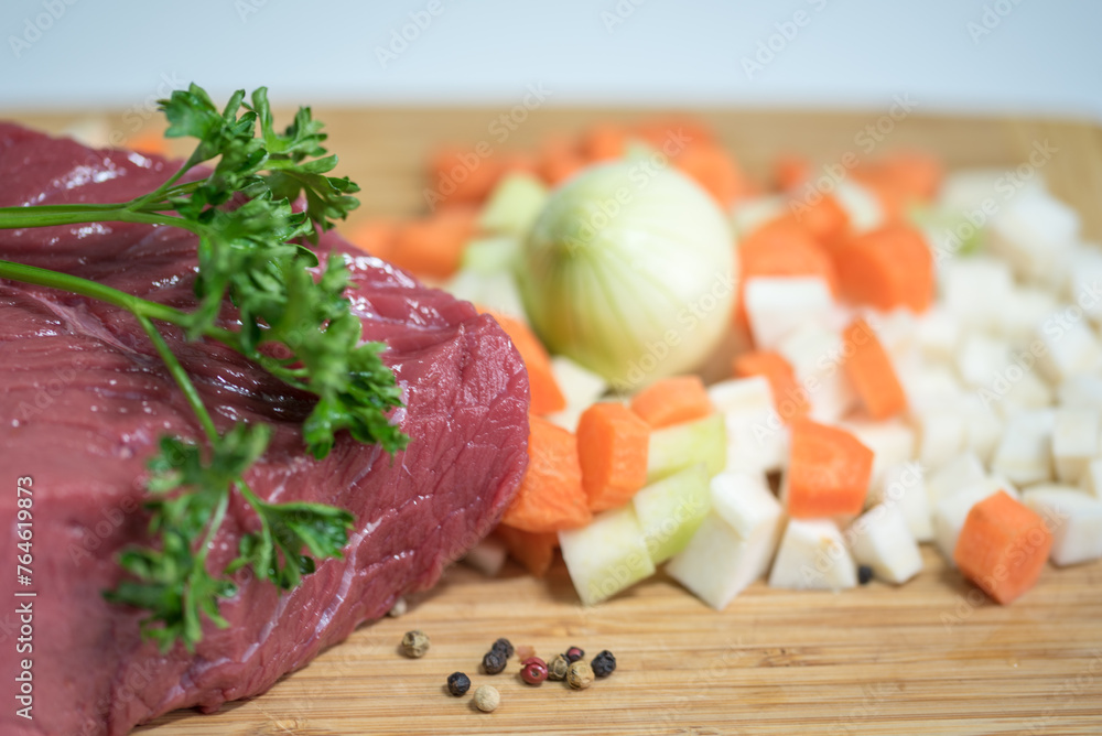 Raw beef meat on a cutting board with fresh vegetable