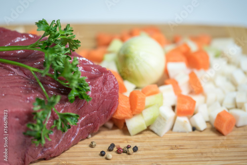 Raw beef meat on a cutting board with fresh vegetable