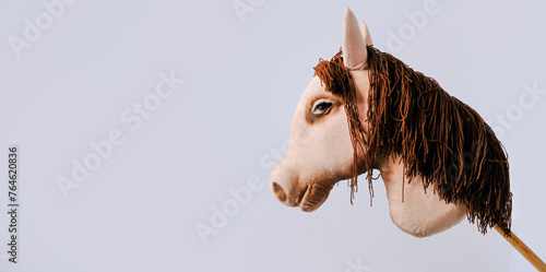 Children's toy - fabric horse head on a stick, on a gray background. Hobbyhorse concept. photo