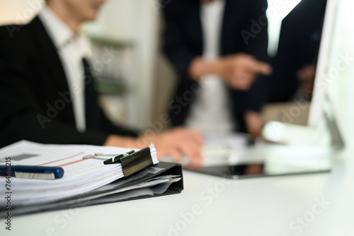 Close up accounting documents on table against businesspeople working in background