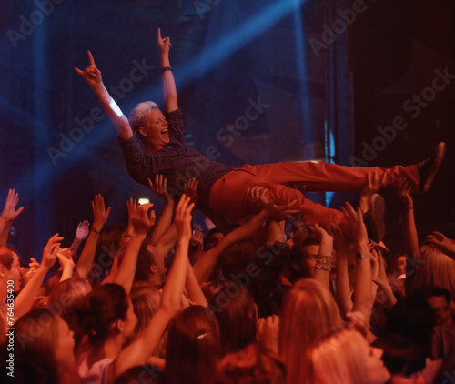 Person, excited and crowd surf at concert, live show and performance for heavy metal band at night. Happy, devil horns and audience carrying man with cheers, energy and joy with loud music in Turkey