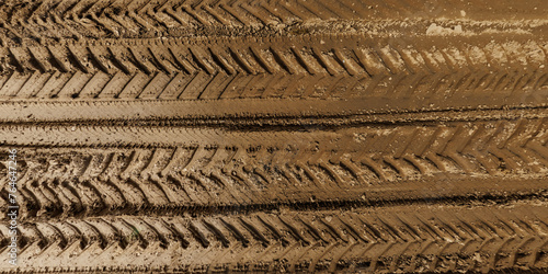 view from above on texture of wet muddy road from above on surface of wet gravel road with tractor tire tracks in countryside