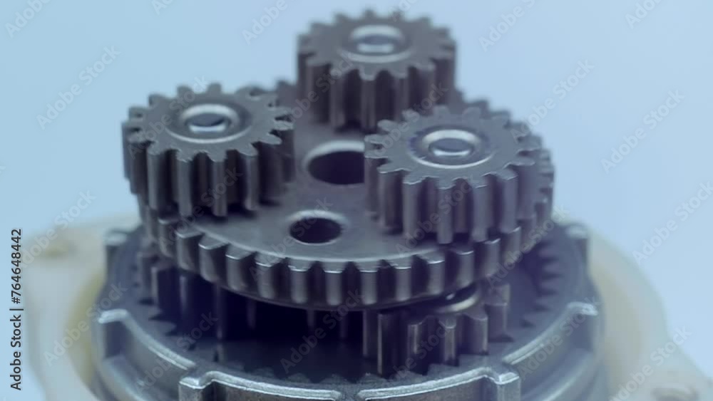Speed reducer motor with many rotating metal gears shining in the light. Closeup. Macro Speed reducer motor with many rotating metal gears shining in the light. Closeup. Macro