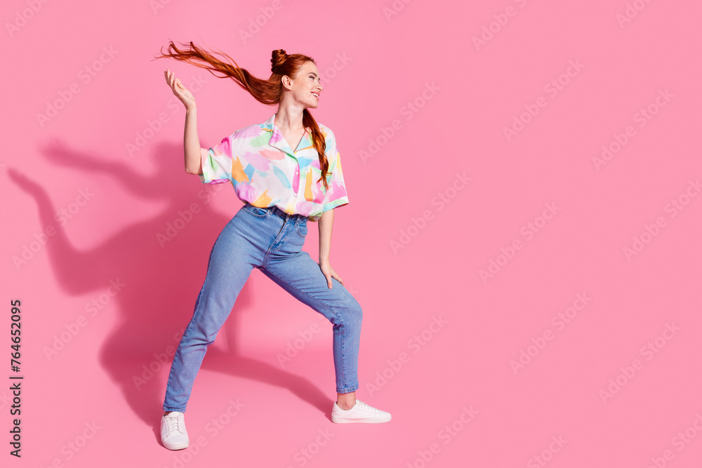 Full size photo of lovely girl with arm fluttering hair dressed colorful blouse look at logo empty space isolated on pink color background Full size photo of lovely girl with arm fluttering hair dressed colorful blouse look at logo empty space isolated on pink color background