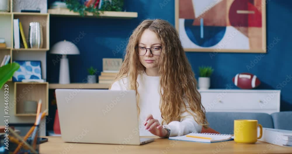 Smiling young woman chatting in internet on laptop indoor home background. Cheerful girl sitting at table desk using notebook pc communicating with friends slow motion. Online connection Smiling young woman chatting in internet on laptop indoor home background. Cheerful girl sitting at table desk using notebook pc communicating with friends slow motion. Online connection