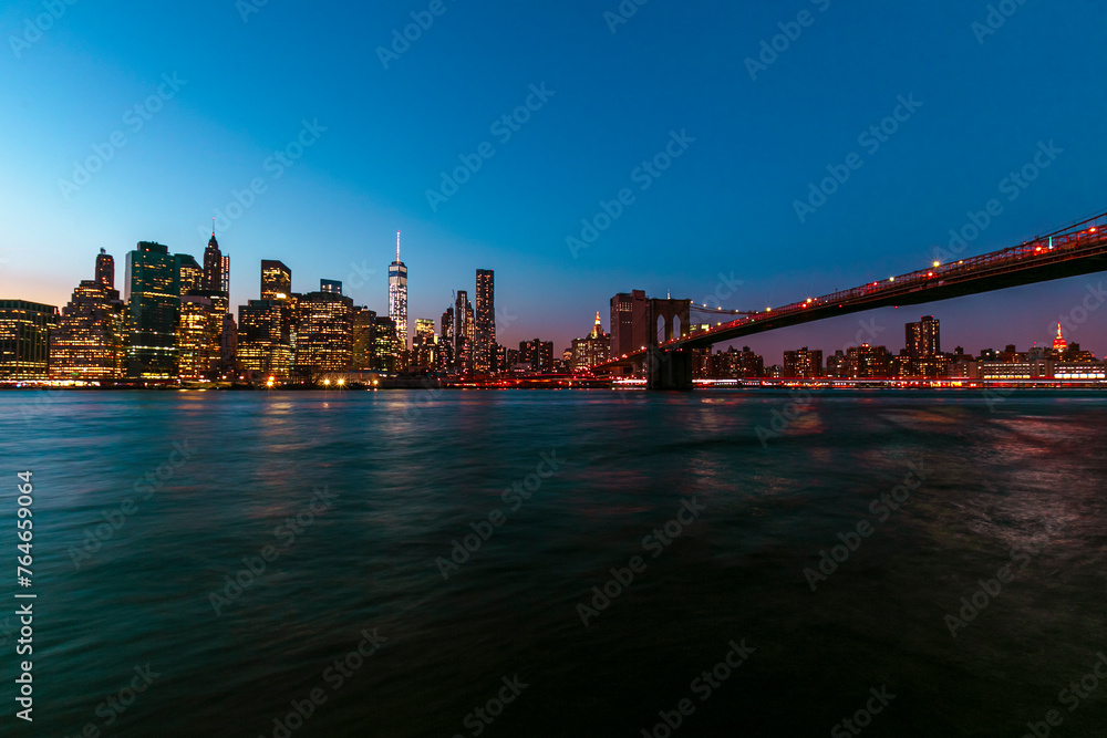  Brooklyn Bridge with lower Manhattan skyline in New York City at night, USA. Long exposure at night