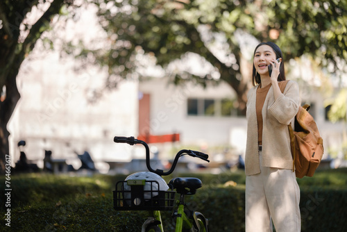 Beautiful woman taking a bike stroll in the park, business woman holding smartphone using bike rental, business woman holding smartphone using bike rental digital phone.