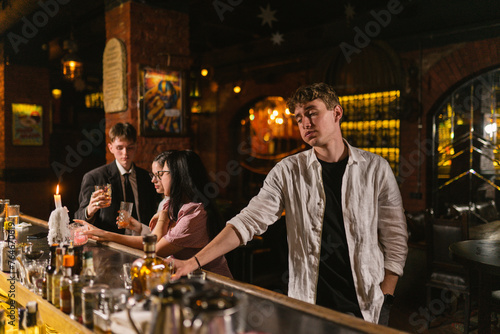 Man in depression drinks lot of strong alcohol at bar. Upset man spends time with huge amount of alcohol in pub with subdued lamps