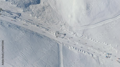 Aerial shot of skiers going up snowy slopes with a lift like ants in Piedmont, Italy, showcasing winter scenery