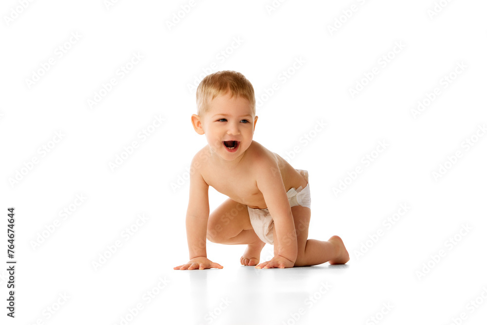 Happy little baby boy in diaper playing, crawling, smiling isolated over white studio background. Positive mood. Concept of childhood and family, care, parenthood, infancy and heath Happy little baby boy in diaper playing, crawling, smiling isolated over white studio background. Positive mood. Concept of childhood and family, care, parenthood, infancy and heath