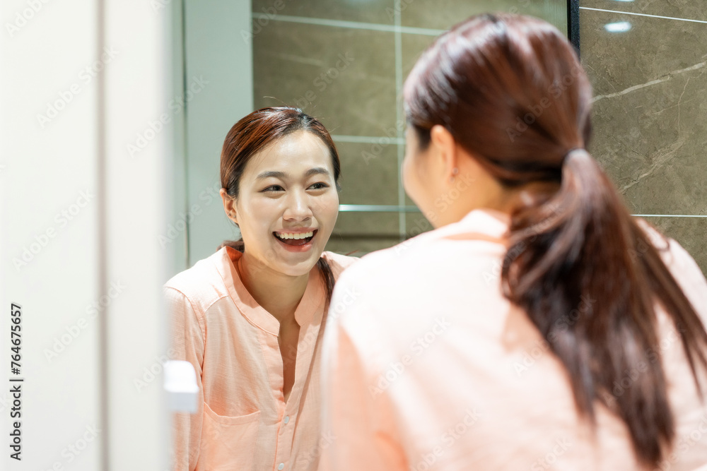 Photo of young Asian woman in bathroom