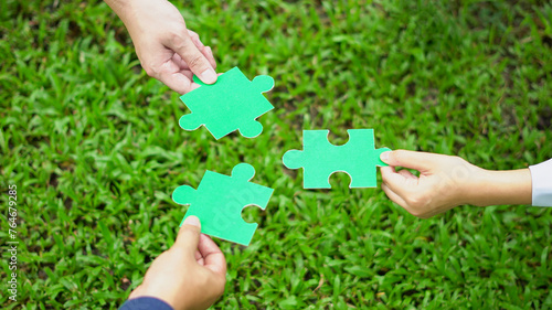 Close-up hand business people of teamwork colleague holding puzzle pieces in a day outdoors on green grass, and green jigsaw copy space for your text use. Team Concept. Top view