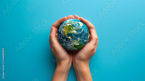 Pair of hands holding a Earth globe on blue background. World Earth Day. Earth Hour, Nature Day,