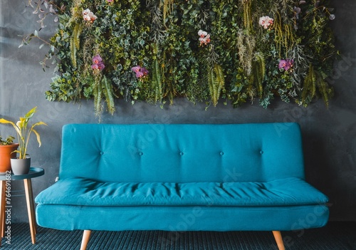 Sofá azul con pared vegetal de fondo