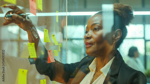 A man in a jacket is placing sticky notes on a glass wall.