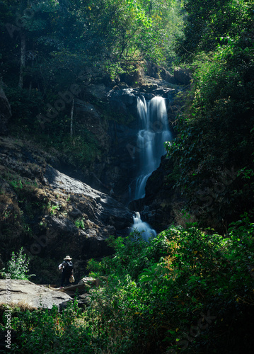 View of young woman standing in front of Iruppu waterfalls in Coorg or Madikeri, Karnataka. Female traveller or tourist enjoy looking at waterfall. Karnataka travel and tourism concept  photo