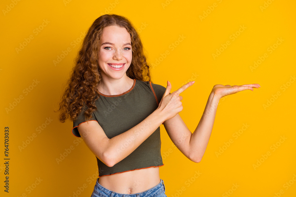 Fototapeta premium Photo of adorable cute girl wear stylish clothes arms demonstrate empty space logo brand isolated on yellow color background