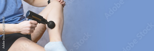 woman massages the calf muscle of her thigh leg a percussion massage gun