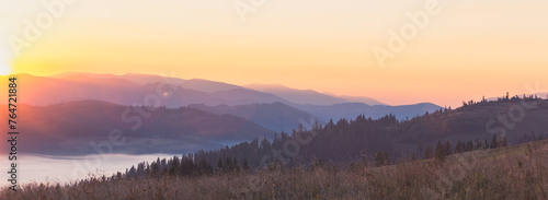Fototapeta Naklejka Na Ścianę i Meble -  Majestic autumn scenery of foggy valley at Carpathian mountain range at early morning sunrise. Beautiful tonal perspective wide angle panorama.